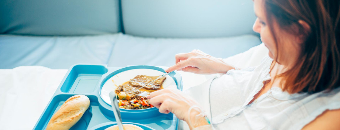 Frau im Krankenbett beim Essen